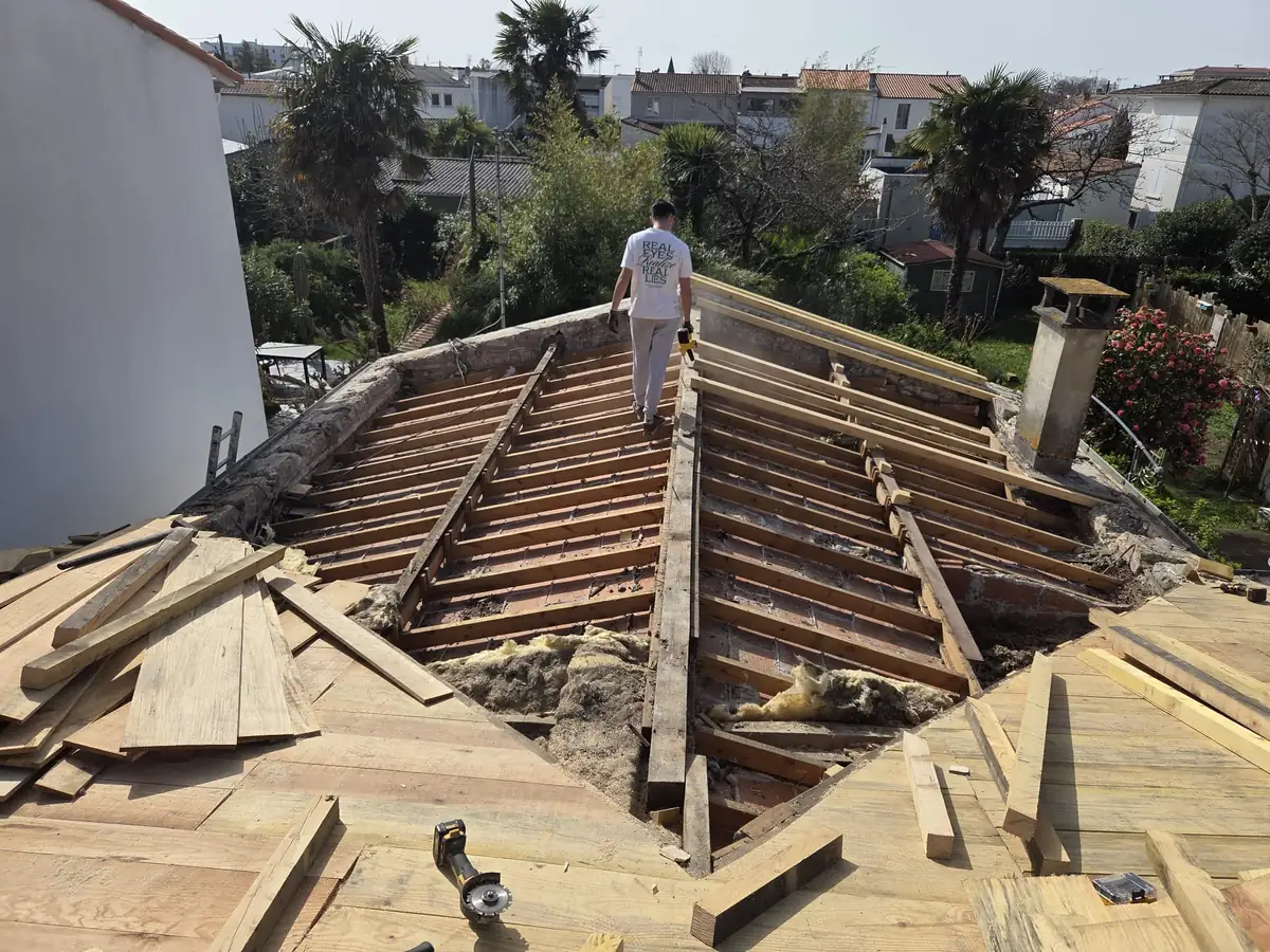 Charpente mise à nu et vieille volige déposée sur une maison de Charente-Maritime, vue depuis le faîtage