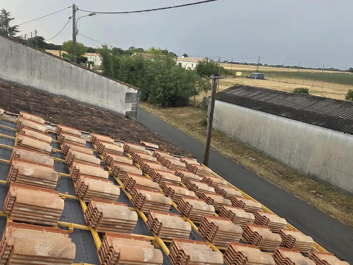 Écran sous-toiture et liteaux jaunes posés, tuiles canal réparties par paquets sur le pan avant repose